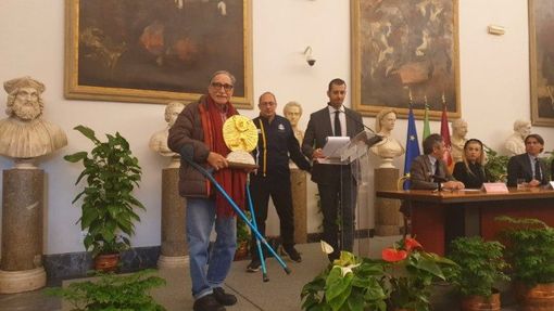Alla presentazione della Maratona di Roma 2023 al Campiodoglio, l'artista Bandfeldt Rosada (a sinistra) presenta la Coppa degli Ultimi da lui realizzata. Al centro, il presidente di Athletica Vaticana Giampaolo Mattei Alla presentazione della Maratona di Roma 2023 al Campiodoglio, l'artista Bandfeldt Rosada (a sinistra) presenta la Coppa degli Ultimi da lui realizzata. Al centro, il presidente di Athletica Vaticana Giampaolo Mattei