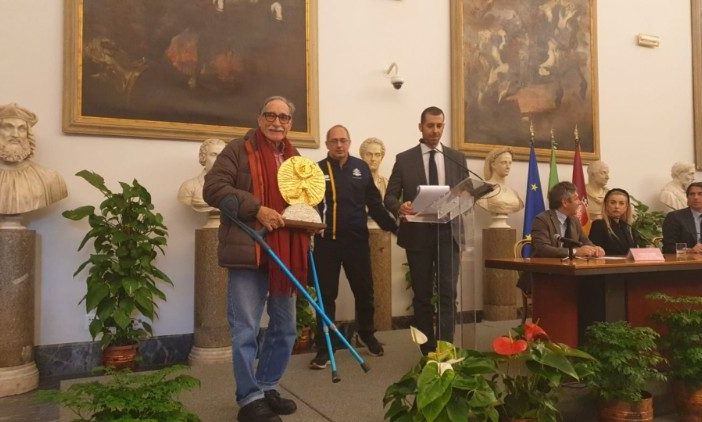 Alla presentazione della Maratona di Roma 2023 al Campiodoglio, l'artista Bandfeldt Rosada (a sinistra) presenta la Coppa degli Ultimi da lui realizzata. Al centro, il presidente di Athletica Vaticana Giampaolo Mattei Alla presentazione della Maratona di Roma 2023 al Campiodoglio, l'artista Bandfeldt Rosada (a sinistra) presenta la Coppa degli Ultimi da lui realizzata. Al centro, il presidente di Athletica Vaticana Giampaolo Mattei